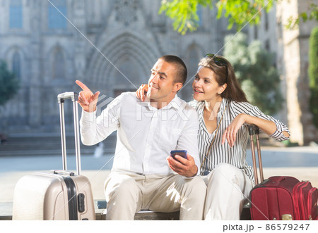 Couple of travelers resting on bench, looking at sights Couple of travelers resting on bench, looking at sights 86579247