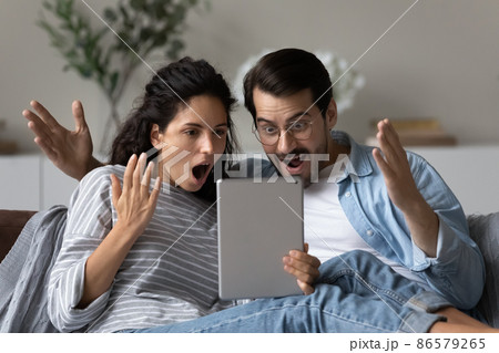 Astonished couple gawp at digital tablet feel amazed by news Astonished couple gawp at digital tablet feel amazed by news 86579265
