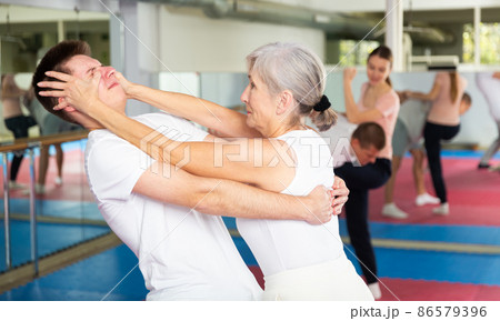 Sportive woman conducts painful reception on the eyes of man in gym. Self defense lessons 86579396