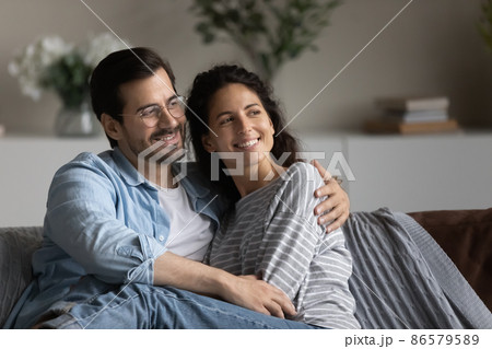Dreamy couple in love sit on sofa looking into distance 86579589