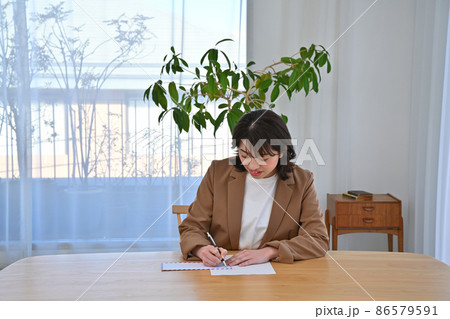 机でエアメールの封筒に住所を書く女性 86579591