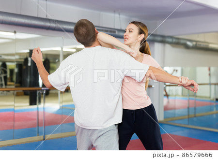 Active girl conducts painful grip on self-defense training in gym 86579666