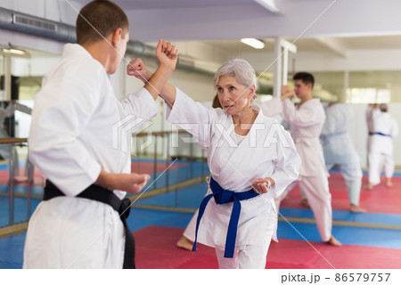 Portrait of woman wearing white kimono sparring with male opponent during martial arts training Portrait of woman wearing white kimono sparring with male opponent during martial arts training 86579757