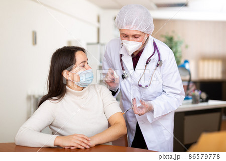 Doctor making vaccine injection to businesswoman 86579778