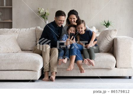 Happy parents and children having fun with smartphone at home 86579812