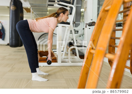 Sporty girl doing romanian deadlift with dumbbells in gym 86579902