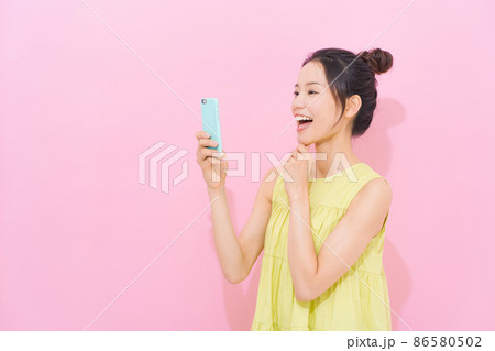 スマホ 女性 ピンク背景 スマホ 女性 ピンク背景 86580502