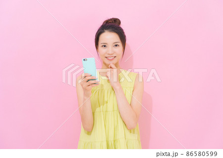 スマホ 女性 ピンク背景 スマホ 女性 ピンク背景 86580599