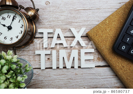 Tax Time alphabet letters with calculator and alarm clock on wooden background Tax Time alphabet letters with calculator and alarm clock on wooden background 86580737
