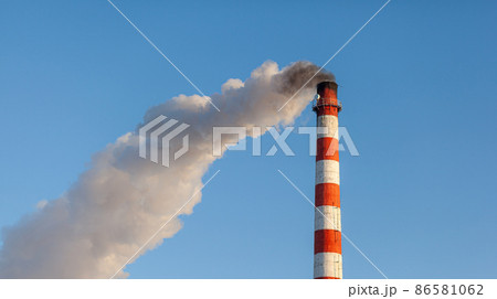 White thick smoke from the boiler room chimney. Smoke against the blue sky. Air pollution. Heating of the city. Industrial zone. 86581062