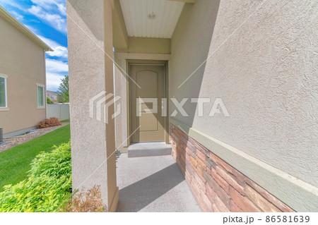 Narrow entrance pathway of a house with a brown cream front door Narrow entrance pathway of a house with a brown cream front door 86581639