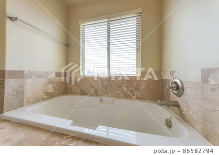 Alcove bathtub in a bathroom with matte marble tiles surround 86582794