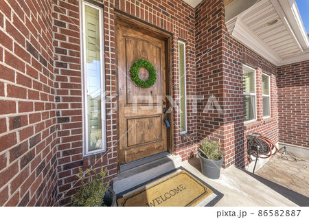 Front porch of a house with wreath on the wooden door with two sidelights 86582887
