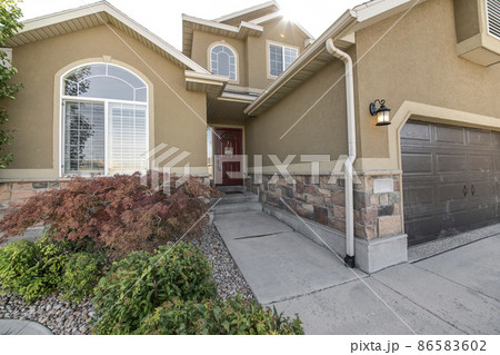 Exterior of a large two-storey house with arched windows and stone veneer siding Exterior of a large two-storey house with arched windows and stone veneer siding 86583602