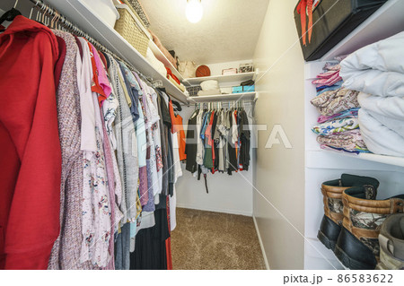 Narrow walk-in closet interior with clothes, shoes and bags 86583622