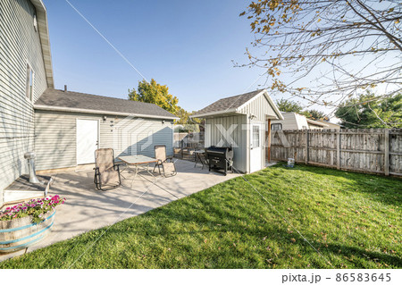 Backyard of a house with white back door and two lounge chairs and table 86583645