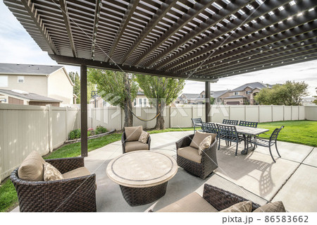 Woven armchairs with cushion and dining table under the pergola roof Woven armchairs with cushion and dining table under the pergola roof 86583662