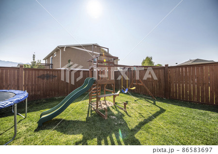 Wooden playground and trampoline at the backyard with lawn 86583697