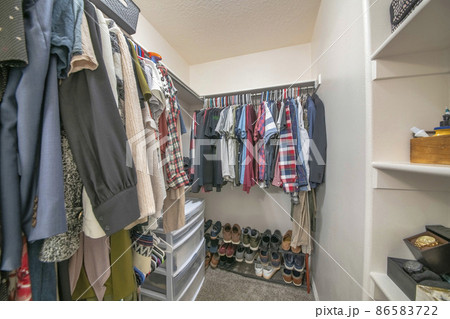 Hanging clothes on a metal rods inside a walk-in closet Hanging clothes on a metal rods inside a walk-in closet 86583722
