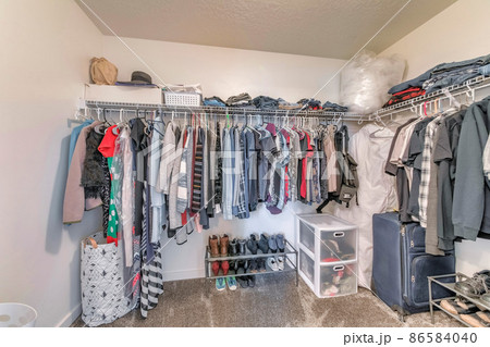 Interior of a small walk-in closet with wall mounted wire shelves Interior of a small walk-in closet with wall mounted wire shelves 86584040