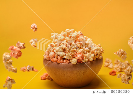 Flying popcorn from wooden bowl isolated on yellow background. 86586380