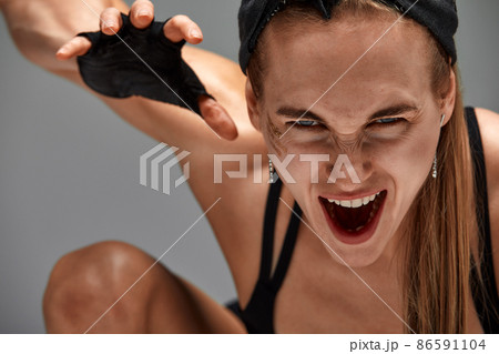 Portrait of female anger, animal instinct, demonstrating their incredible flexibility with the movement of animal flow in the studio on a gray background. 86591104