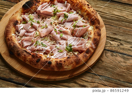 Fresh pizza with ham and pineapple on wooden table in restaurant. 86591249