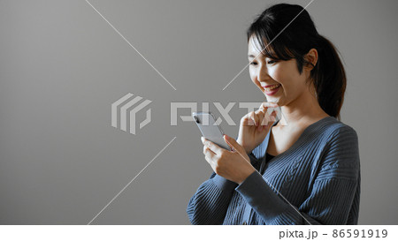 携帯電話を操作する若い女性 携帯電話を操作する若い女性 86591919