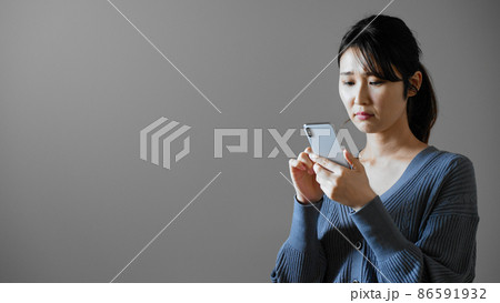携帯電話を操作する若い女性 86591932