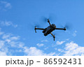 quadcopter drone flying by on the background of blue sky with clouds view from below 86592431