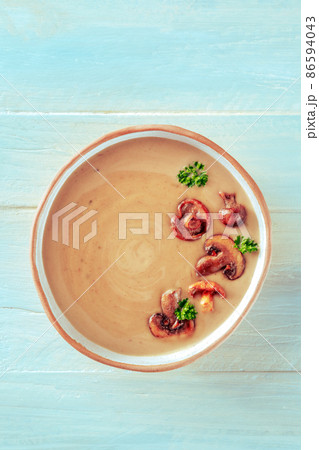 Mushroom soup in a rustic bowl, overhead shot on a teal wooden table Mushroom soup in a rustic bowl, overhead shot on a teal wooden table 86594043