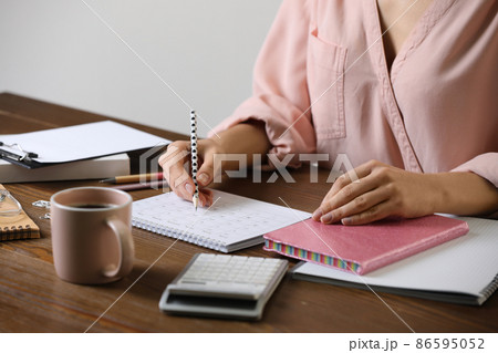 Woman marking date in calendar at wooden table, closeup 86595052
