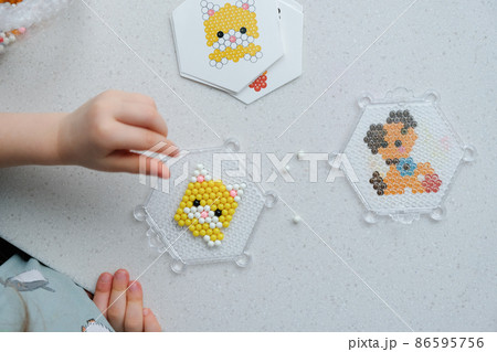 The child lays out an aqua mosaic in the form of a cat's muzzle The child lays out an aqua mosaic in the form of a cat's muzzle 86595756