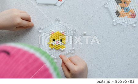 The child lays out an aqua mosaic in the form of a cat's muzzle 86595783