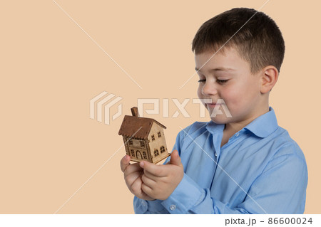 the concept of buying real estate, a dreaming boy, holding a small wooden house, smiling looks at the house the concept of buying real estate, a dreaming boy, holding a small wooden house, smiling looks at the house 86600024
