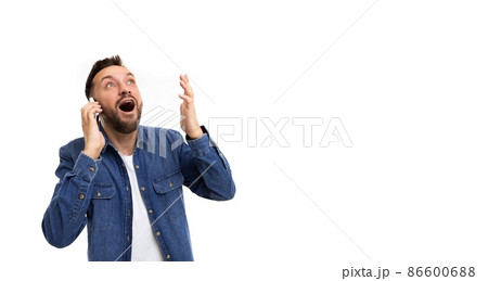 A man speaks on the phone gesturing with his hands with an open mouth, a smile and wide eyes in A man speaks on the phone gesturing with his hands with an open mouth, a smile and wide eyes in 86600688