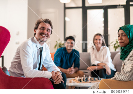 Multiethnic group of business people playing chess while having a break in relaxation area at modern startup office. 86602974