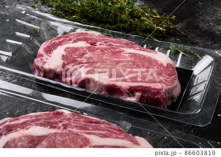 Fresh raw red meat vacuum sealed in plastic, on black dark stone table background 86603819