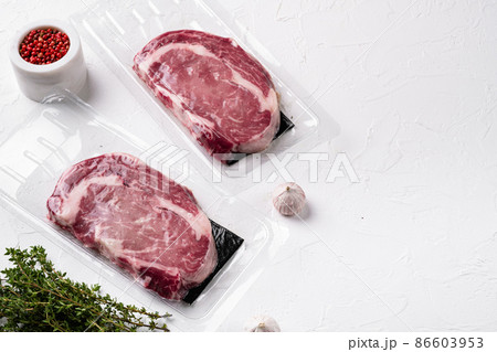 Fresh raw red meat vacuum sealed in plastic, on white stone table background, with copy space for text 86603953