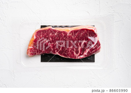 Raw marbled beef steaks in vacuum pack, on white stone table background, top view flat lay, with copy space for text 86603990