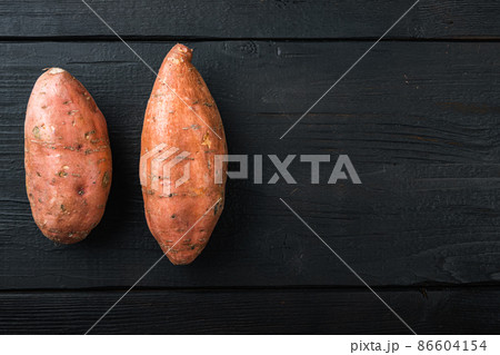 Sweet potato or batat, on black wooden background, top view with space for text 86604154