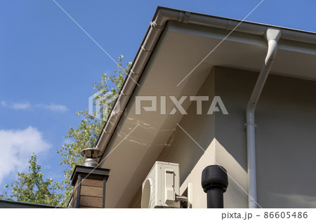 Exhaust air pipes, air conditioner and white rain gutter on private house roof. Metallic Guttering System and ventilation pipes exterior Exhaust air pipes, air conditioner and white rain gutter on private house roof. Metallic Guttering System and ventilation pipes exterior 86605486