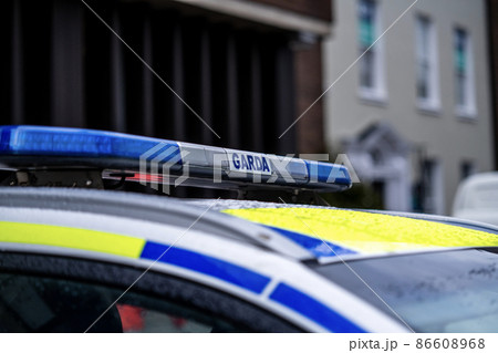 View of police emblems in Ireland, emblem on building, car, and street lantern 86608968
