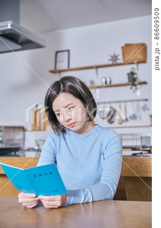 年金手帳を見つめて老後が不安になる若い女性 86609509