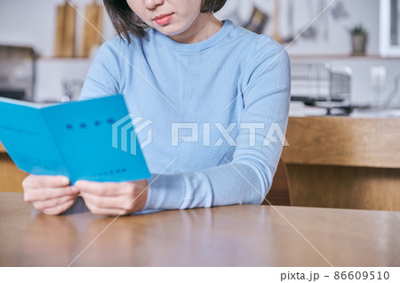 年金手帳を見つめて老後が不安になる若い女性 86609510