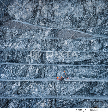 Stepped wall of diabase stone quarry with red drilling rig 86609662