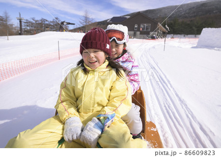 スキー場のゲレンデで雪遊びする小学生の女の子 86609823