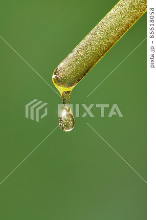 A drop of cosmetic aromatic oil drips from the pipette. Front view. A drop of cosmetic aromatic oil drips from the pipette. Front view. 86618058