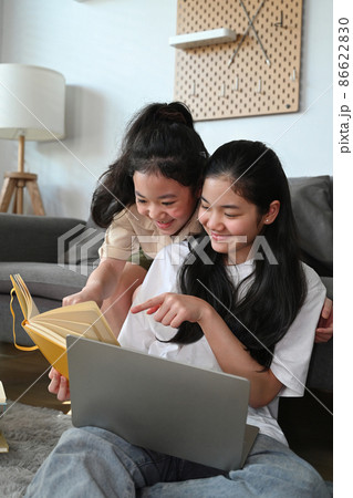 Two lovely young teenage girls doing homework together and helping each other. 86622830