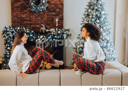 Two female student friends sitting on the couch at home. 86622927